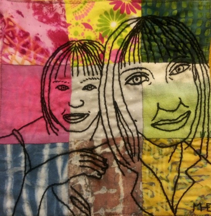 a closeup portrait of a mother with her child looking over her shoulder stitched in black thread over a 3x3 grid patchwork of colorful patterned fabrics
